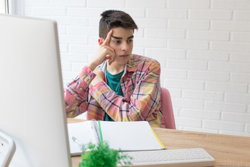 thoughtful student on the desk with computer and books