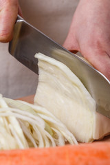 young woman in a gray apron cut cabbage