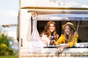Happy pretty girls in the van are traveling, with a camera. Unforgettable trip with friends,...