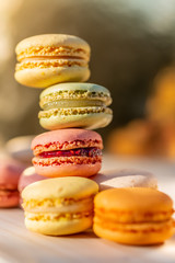 Delicious sweet airy colored french pastries. Sweets macarons in the summer evening in an orchard. Blurred background. Soft focus.