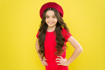 Smiling child. Kid happy cute face adorable curly hair yellow background. Lucky and beautiful. Beauty tips for tidy hair. Kid girl long healthy shiny hair wear red hat. Little girl with long hair