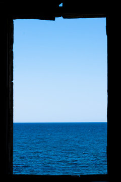Window frame in ruins on the sea