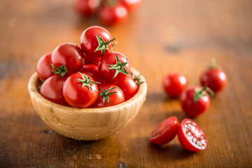Fototapeta na wymiar Fresh cherry tomatoes in wooden bowl on wooden table