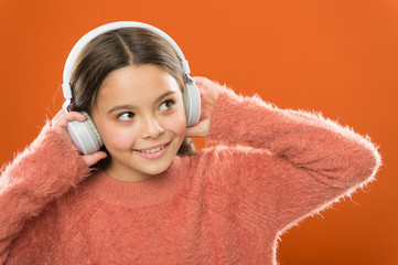 Modern technology is amazing. Small child wearing headphones with bluetooth technology. Little girl...