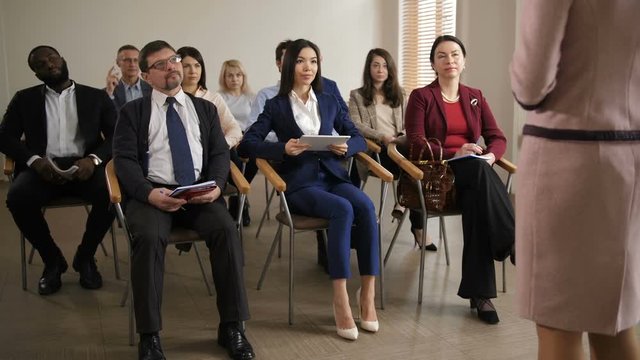 Interested diverse multi ethnic team of employees taking part at corporate business meeting. Group of co-workers intently listening to executive manager presenting new company's strategy
