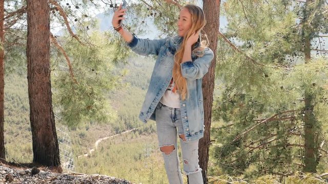 Young woman taking selfie with mobile phone outdoors
