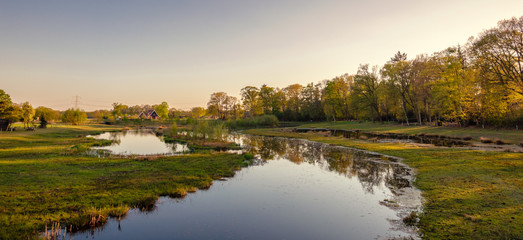 Naklejka na ściany i meble Calm river along a walking trail in a Dutch farm landscape during sunset. It is located near the small neighbourhood called Tusveld, near the town of Almelo in the Eastern Netherlands.