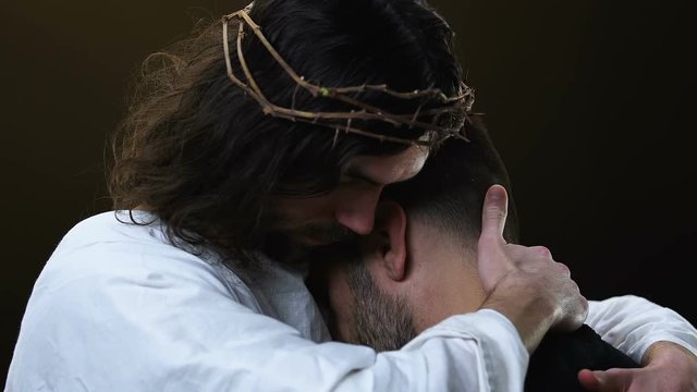 Kind Jesus Christ hugging poor man isolated on dark background, forgiveness