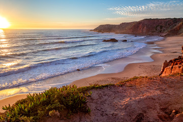 Fototapeta na wymiar Sunset at Praia do Amado in the Costa Vicentina natural park at the Atlantic Ocean at the Algarve, Portugal.