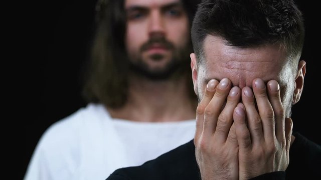 Lonely man closing face, Jesus Christ taking males hand away, Epiphany concept