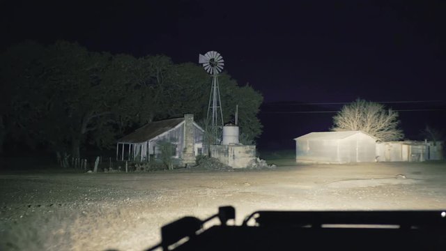 A nighttime truck-lit tracking shot of a creepy abandoned town in the American mid-west.