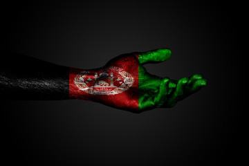 Outstretched hand with a drawn Afghanistan flag, a sign of help or a request, on a dark background.