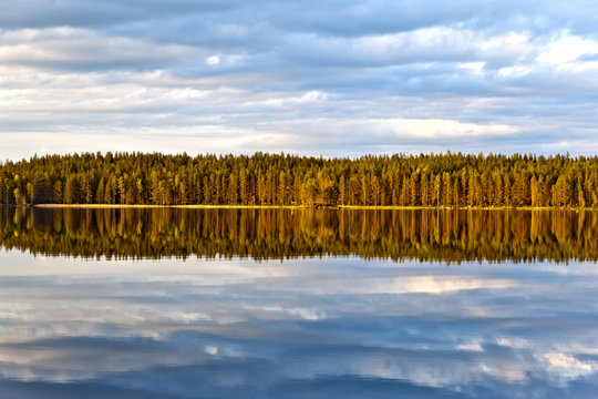 Beautiful volumetric clouds on a sunny day over a quiet forest lake
