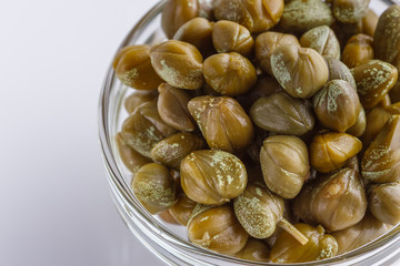 Pickled capers on a white acrylic background