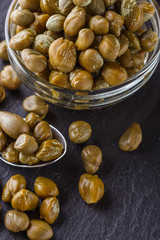 pickled capers on a dark stone background