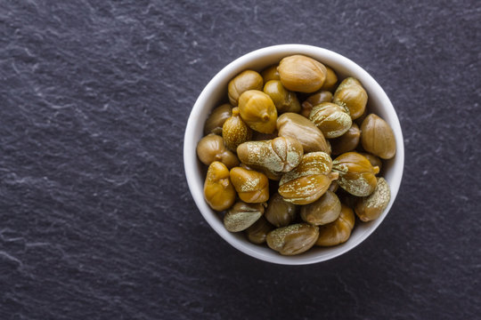pickled capers on a dark stone background
