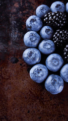 Blueberries and blackberries on dark background. Fresh berries for vegan. Assorted berries on rusty background. Flat lay