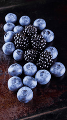 Blueberries and blackberries on dark background. Fresh berries for vegan. Assorted berries on rusty background. Flat lay