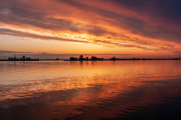 Fototapeta na wymiar dark orange sunset spring evening on the river or reservoir