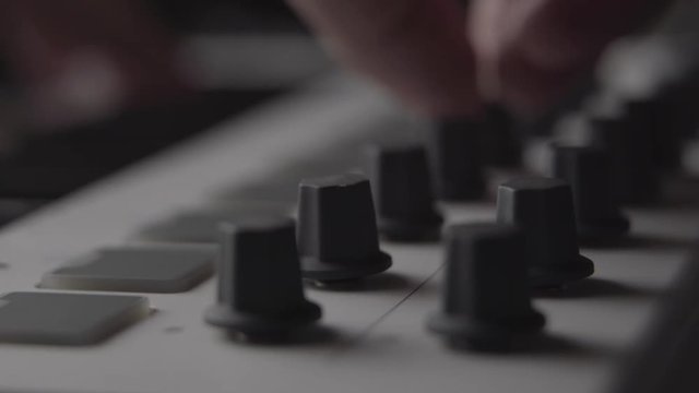 DJ adjusting audio effect knobs on MIDI keyboard while making music