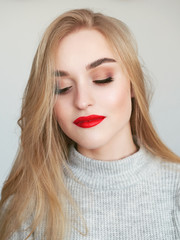 Closeup natural light beauty portrait of blonde woman model with vibrant saturated red lips bright lips makeup, cheekbones and healthy shiny skin.