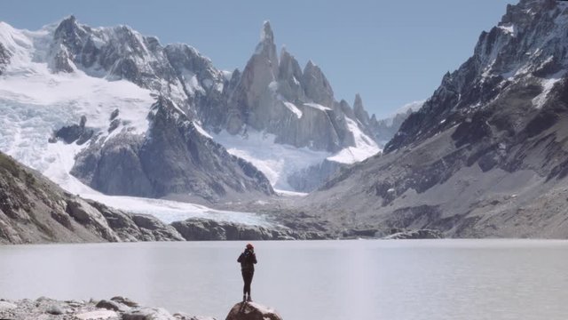 Female backpacker contemplating the landscape of the snowy peaks of the patagonia mountain range. Los glaciares national park panorama. 4k