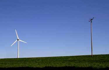 Fototapeta premium Wind turbine and power line on a field against the blue sky