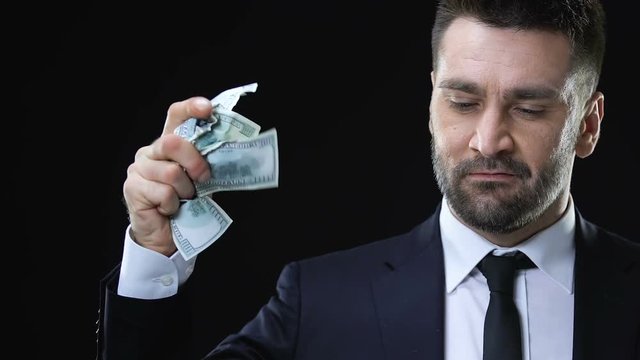 Confident business man clenching and throwing dollar banknotes, life values
