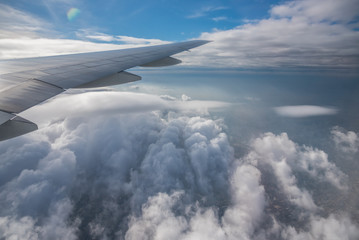 Fototapeta premium Aerial View from an Airplane. Flying above Clouds at Sunrise