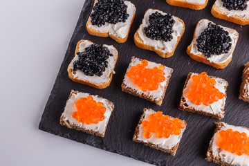Snack with red and black caviar on a stone plate
