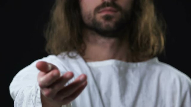 Jesus Christ in robe reaching out his hand to camera, saving sinner souls