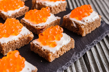Snack with red and black caviar on a stone plate