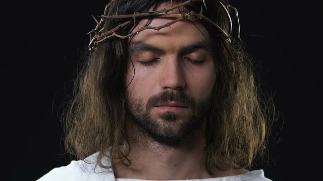 Crying Jesus Christ with eyes closed feeling sorrow for peoples sins, darkness