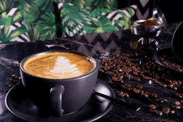 Cup of cappuccino coffee on dark table with coffee beanss