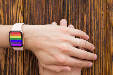 17 may international day against homophobia, transphobia and biphobia. Male hand with a pink clock on a wooden background with a space for the text