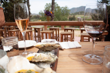 Stylized cup for rosé wine on tabletop Glass of red wine with oysters for pairing on the outside surrounded by the mountains of Baja California north