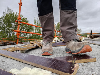 A construction worker has an acciden while walks through a site with debris and stepping on a nail