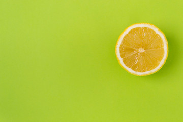 Round slice of yellow lemon, on a green background.