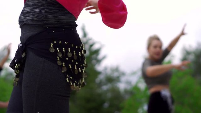 woman is training to move like in oriental dance, close-up of her hips with belt with coins