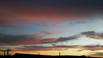 Fundo com n&uacute;vens escuras e vermelhas formando arte no c&eacute;u azul