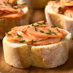 Smoked salmon sandwiches with chives, photographed with natural light (Selective Focus, Focus on the front of the salmon on the first bread)