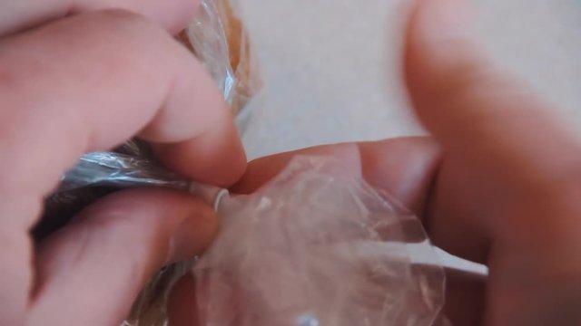 Male hands open plastic bag with bread on the table. The packaging is closed on a latch. Close up shot