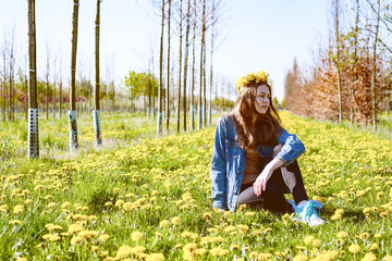 young beautiful girl alone with nature among beautiful yellow dandelions