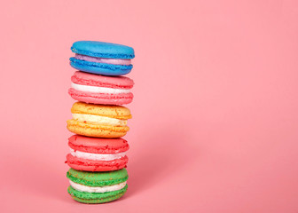 Macaron cookies stacked on pink background, colorful traditional french pastry.