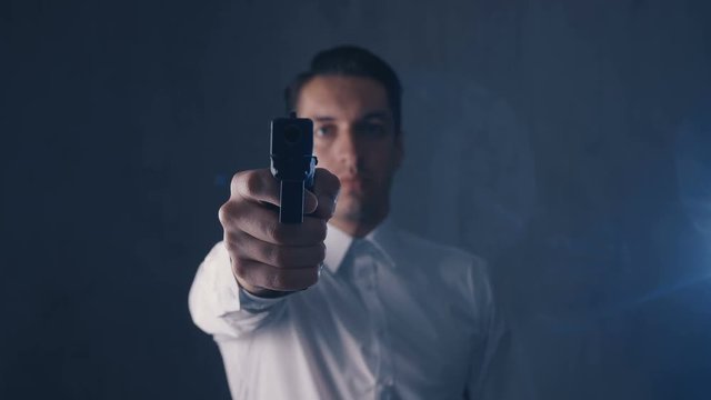 Mafia man pointing gun into a camera. Focus on gun.