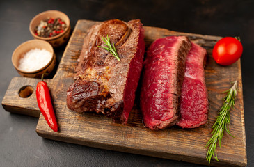 Grilled rib eye beef steak with herbs and spices on a stone background