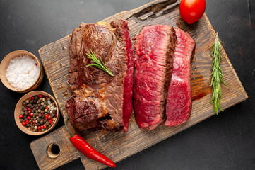 Grilled rib eye beef steak with herbs and spices on a stone background