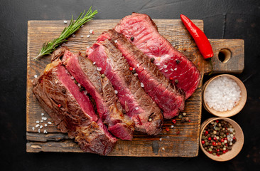 Grilled rib eye beef steak with herbs and spices on a stone background