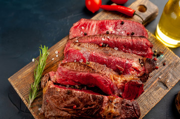Grilled rib eye beef steak with herbs and spices on a stone background