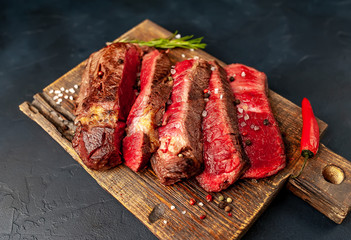 Grilled rib eye beef steak with herbs and spices on a stone background